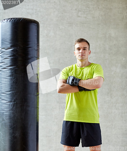 Image of man with boxing gloves and punching bag in gym