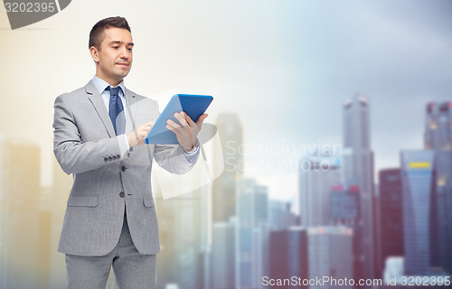 Image of happy businessman in suit holding tablet pc
