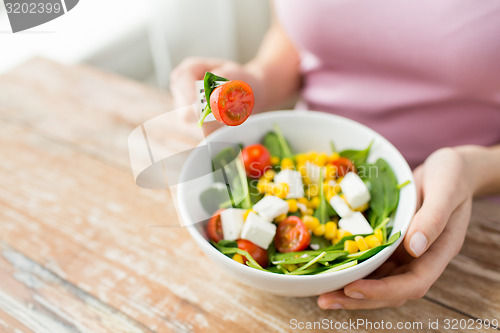 Image of close up of young woman eating salad at home