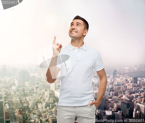 Image of smiling man pointing finger up over city