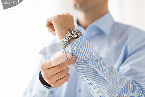 Image of close up of man fastening buttons on shirt sleeve