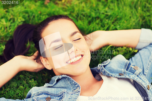 Image of smiling young girl with closed eyes lying on grass