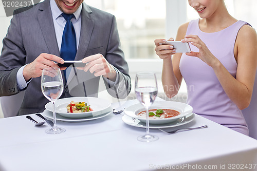 Image of close up of couple with smartphones at restaurant