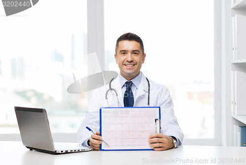 Image of happy doctor with clipboard and laptop in office