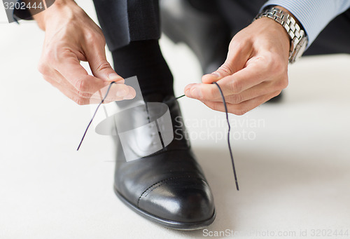 Image of close up of man leg and hands tying shoe laces