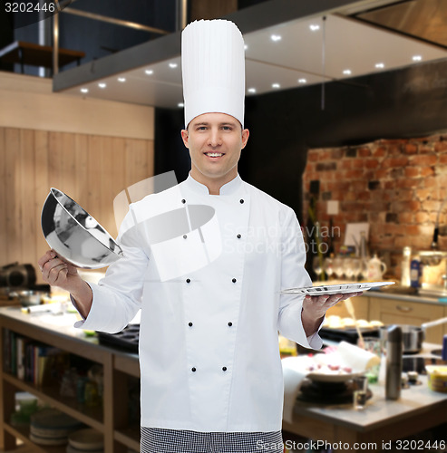 Image of happy male chef cook opening cloche