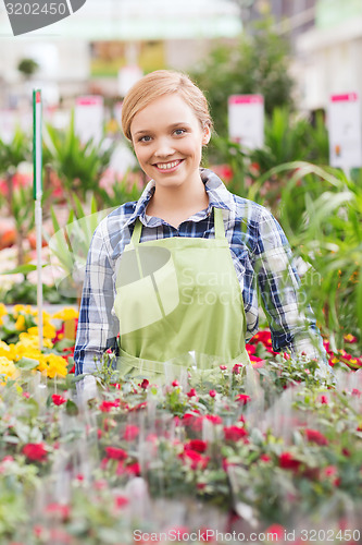 Image of happy woman with flowers in greenhouse