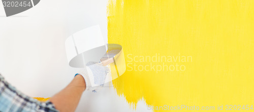 Image of close up of male in gloves painting a wall