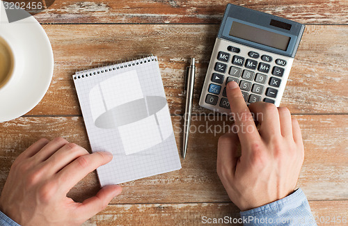 Image of close up of hands with calculator and notebook
