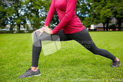 Image of close up of woman stretching leg outdoors