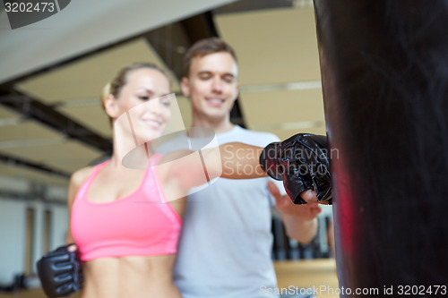 Image of happy woman with personal trainer boxing in gym