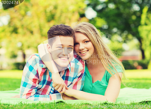 Image of smiling couple lying on blanket in park