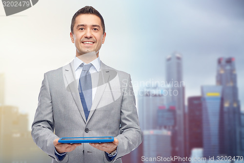Image of happy businessman in suit holding tablet pc