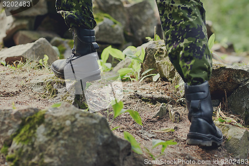 Image of close up of soldier climbing on rocks in forest