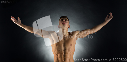 Image of young male bodybuilder with raised hands