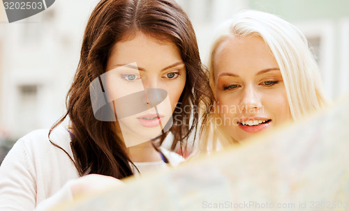 Image of beautiful girls looking into tourist map in city