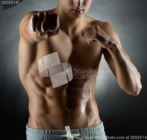 Image of young man on fighting stand over black background