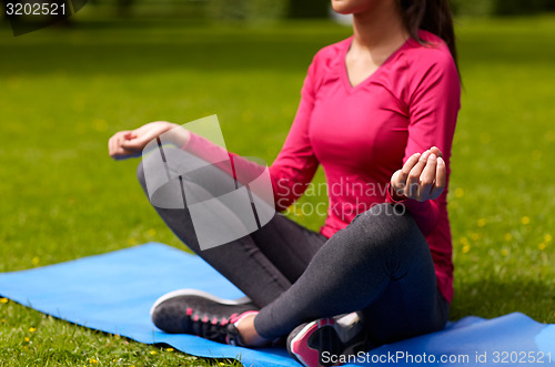 Image of close up of woman meditating on mat outdoors