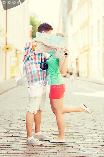 Image of smiling couple with map and photo camera in city