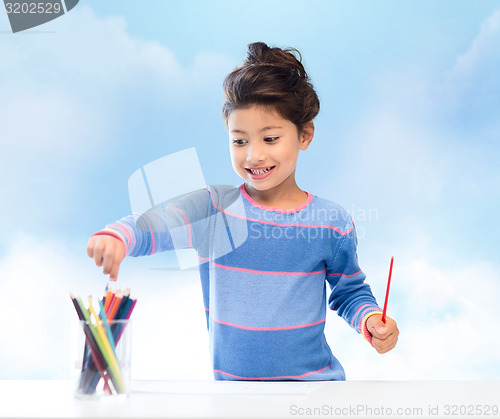 Image of happy little girl drawing with coloring pencils