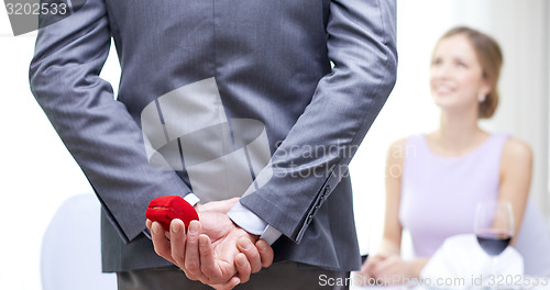 Image of close up of man hiding red box behind from woman