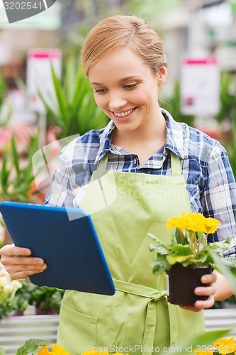 Image of happy woman with tablet pc in greenhouse