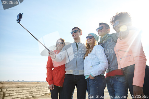 Image of smiling friends taking selfie with smartphone