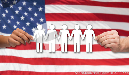 Image of hands holding people pictogram over american flag