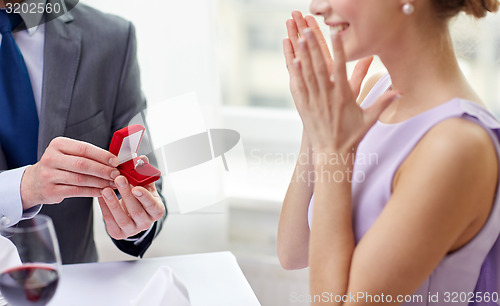 Image of excited young woman and boyfriend giving her ring