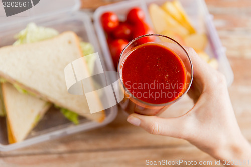 Image of close up of woman hand holding tomato juice glass