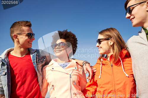 Image of happy teenage friends in shades talking on street