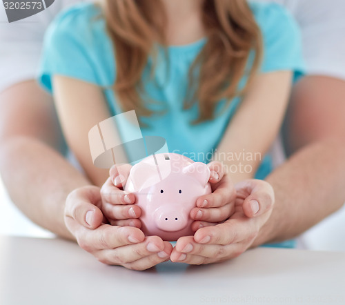 Image of close up of family hands with piggy bank