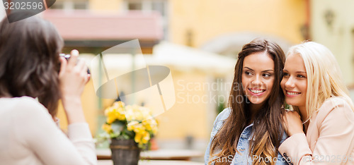 Image of beautiful girls taking picture in cafe in city