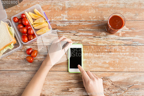 Image of close up of hands with smartphone food on table