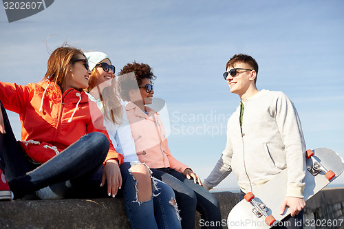 Image of happy teenage friends with longboard on street