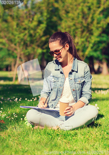 Image of smiling young girl with notebook and coffee cup