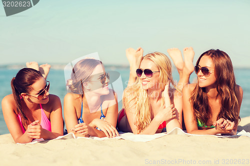 Image of group of smiling women in sunglasses on beach