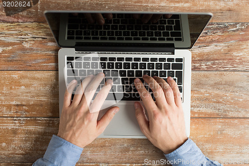 Image of close up of male hands with laptop typing