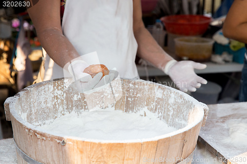 Image of close up of cook hands with meatball and flour