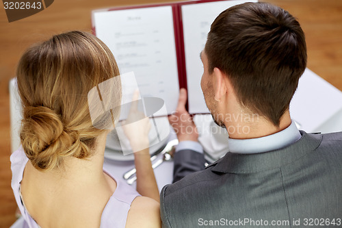 Image of close up of happy couple with menu at restaurant