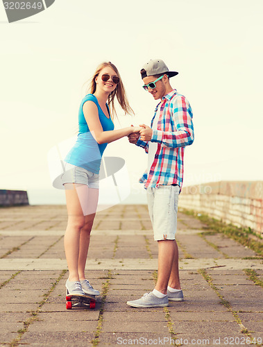 Image of smiling couple with skateboard outdoors