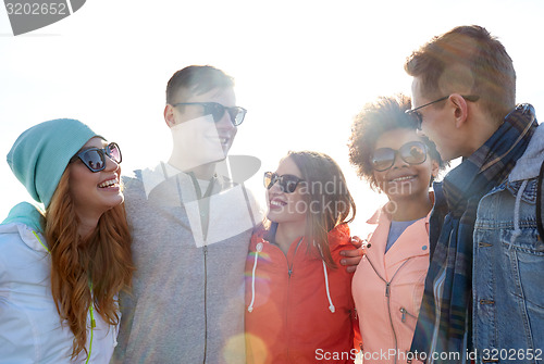 Image of happy teenage friends in shades talking on street