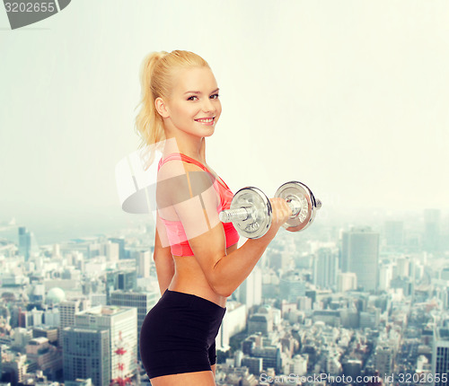 Image of young sporty woman with heavy steel dumbbell