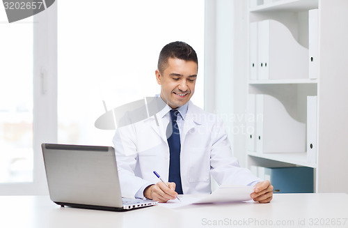 Image of smiling male doctor with laptop in medical office