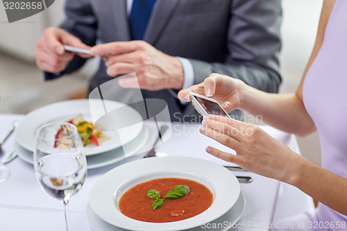 Image of close up of couple with smartphones at restaurant