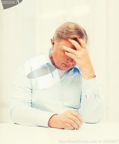 Image of stressed old man holding head at home