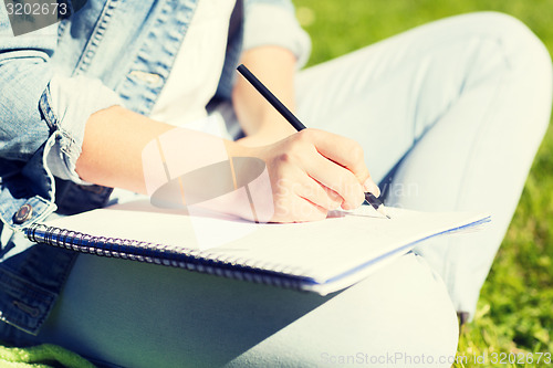 Image of close up of girl with notebook writing in park