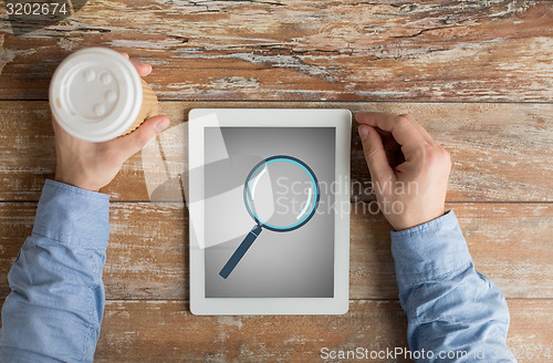 Image of close up of male hands with magnifier on tablet pc