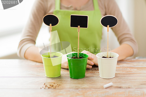 Image of close up of woman over pots with soil and signs