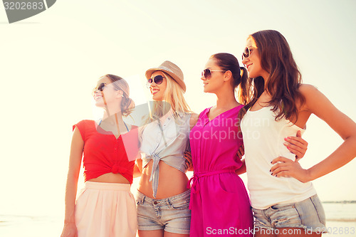 Image of group of smiling women in sunglasses on beach